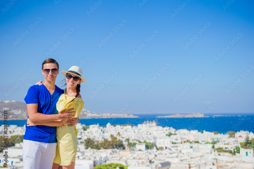 Beautiful young couple at Mykonos island, Cyclades. Tourists enjoy their greek vacation in Greece background famous Mykonos village