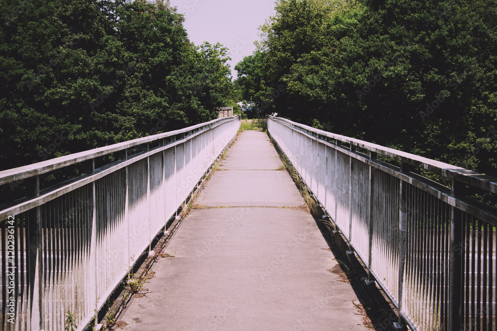 View along a long footbridge with railings on either side Vintag