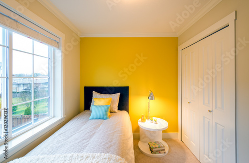 Modern yellow bedroom interior with blue and yellow pillows in a  luxury house.