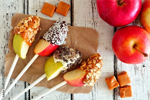фотографія Autumn apples slices dipped with chocolate and caramel, scene on a rustic white
