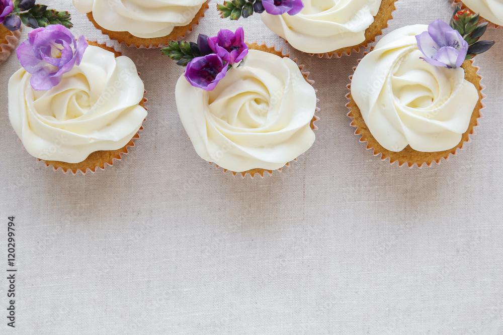 whipped cream frosting vanilla cupcakes with purple edible flowers