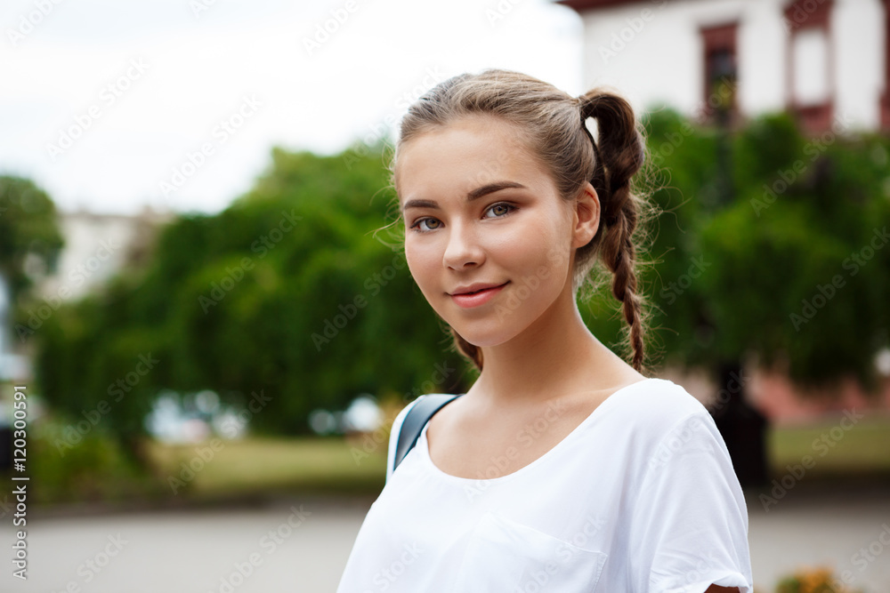 Young beautiful cheerful female student smiling, holding folders outdoors, park background. Young beautiful cheerful female student smiling, holding folders outdoors, park background.