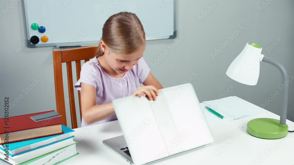 Child shopping online. Portrait girl 7-8 years opening laptop and using credit card and smiling at camera. Thumb up. Ok Child shopping online. Portrait girl 7-8 years opening laptop and using credit card and smiling at camera. Thumb up. Ok