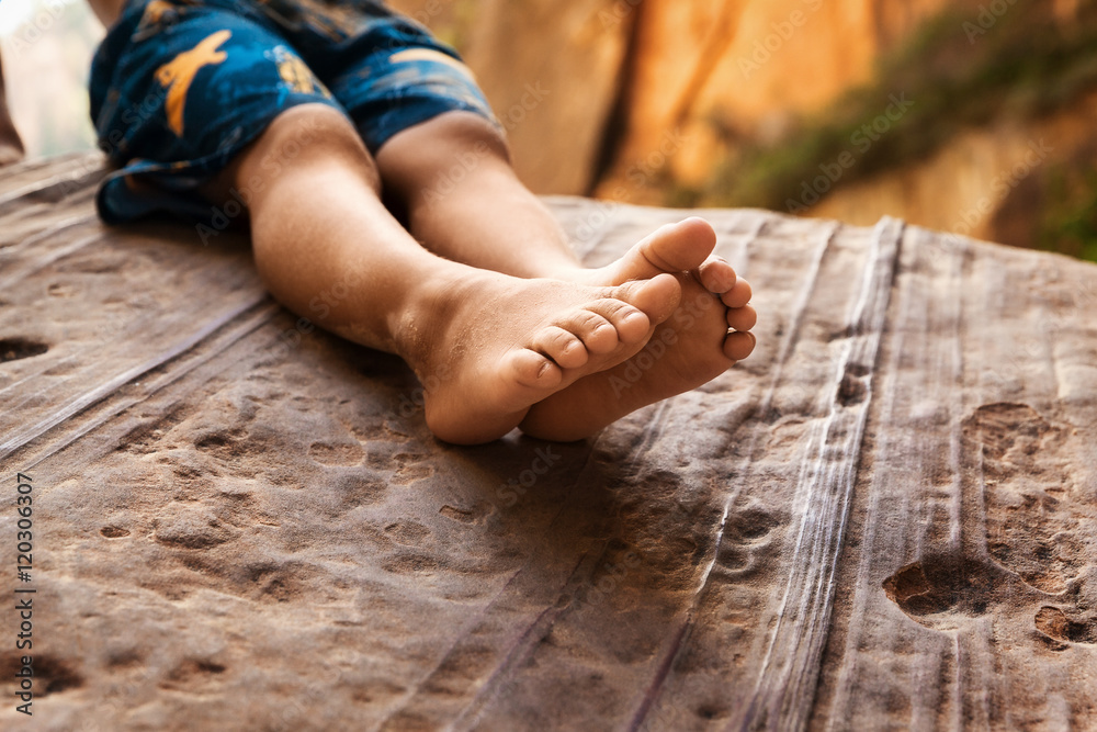 Young boy sitting on rock with bare feet Young boy sitting on rock with bare feet