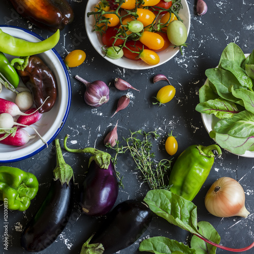 Foto Fresh vegetables - radishes, eggplant, pepper, tomatoes, onion, garlic on a dark wooden background