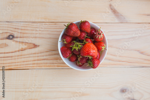 plate of ripe strawberries on wooden background