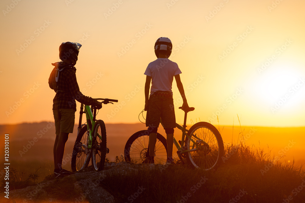 Φωτογραφία Silhouette of young bikers staying with mountain bicycles on the top of mountain