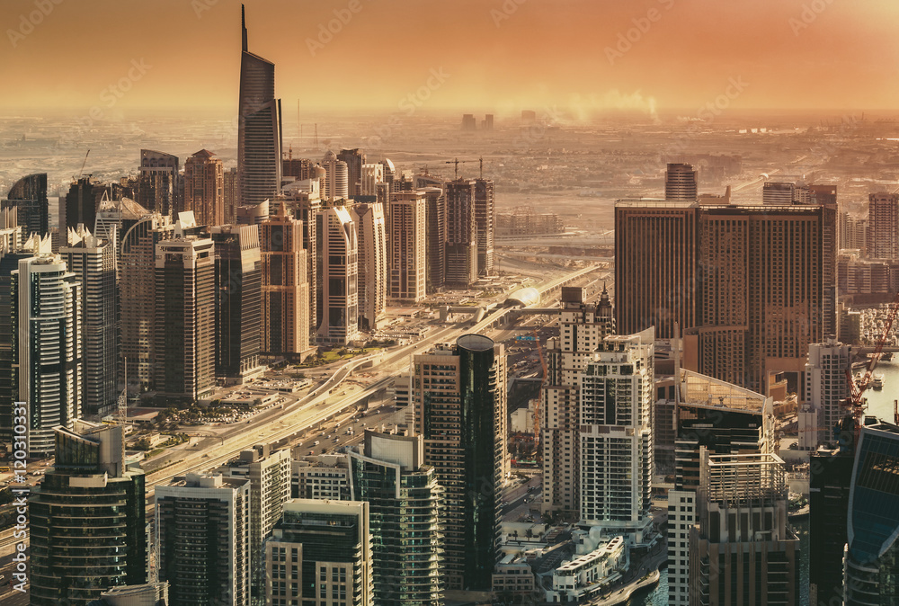Scenic view of modern city architecture in dramatic sunset light. Aerial skyline of Dubai Marina, UAE, with skyscrapers. Architecture and travel background.