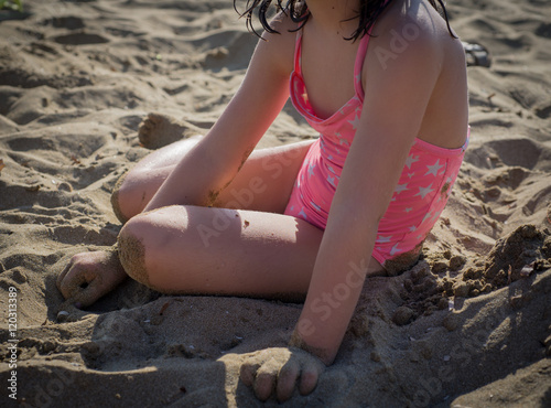 Photography petite fille en maillot de bain assise détendue sur le sable