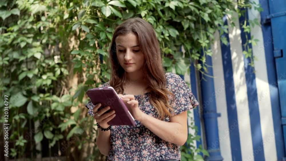 Girl browsing internet on tablet and smiling to the camera
Girl browsing internet on tablet and smiling to the camera