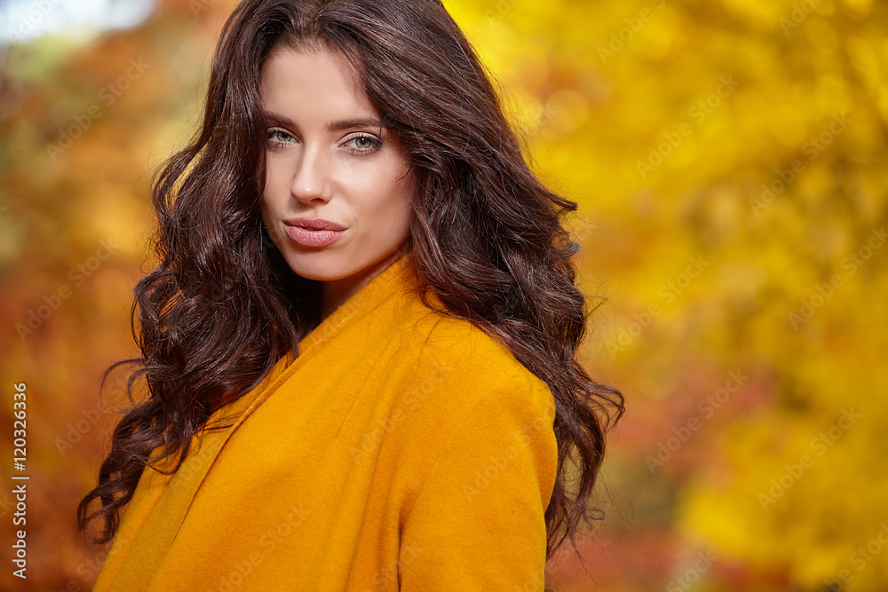 Beautiful elegant woman standing in a park in autumn