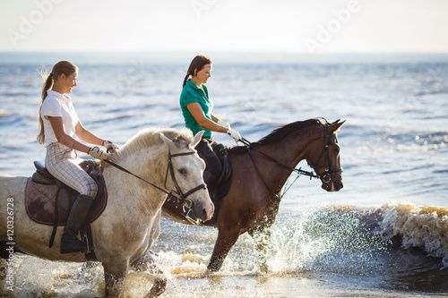 Two pretty girls riding horses in river water