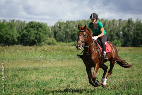 Fényképezés Young woman riding a horse on the green field