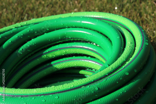 Garden hose bundle on the mown lawn in the summer garden photo