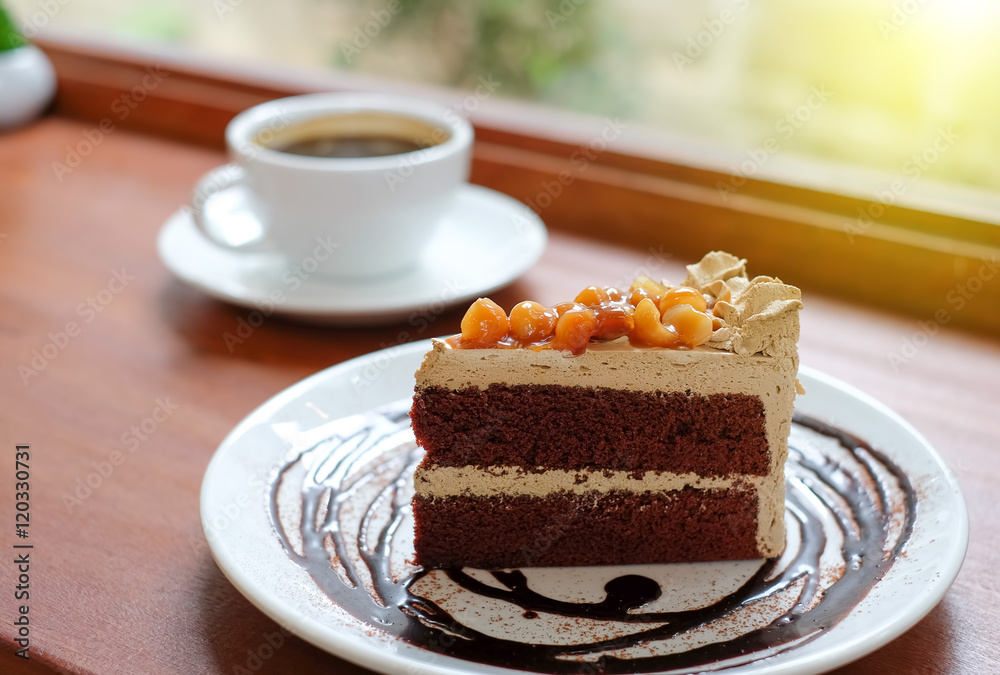 Macadamia chocolate cake with white coffee cup on wooden floor.