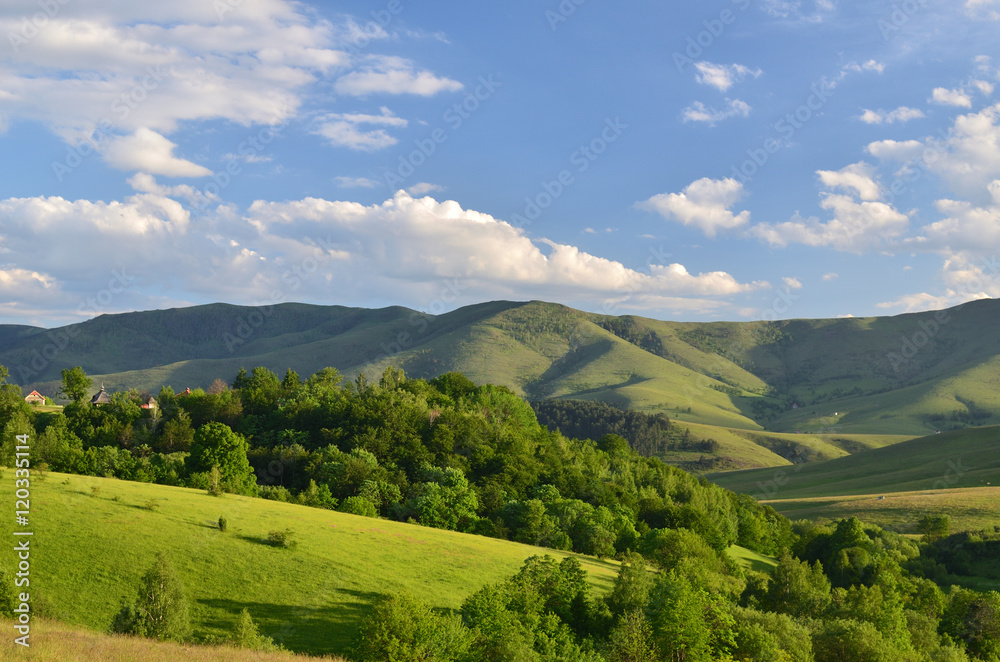 Landscape of Zlatibor Mountain. Green meadows and hills under blue sky with clouds in springtime