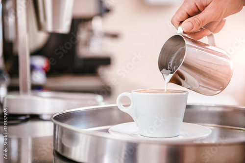 Woman pouring milk in coffee