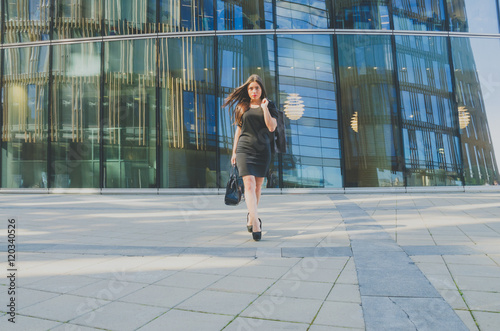 beautiful girl in black with a bag in hand on the background of the business center