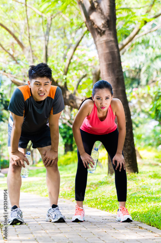 Asian couple take breathless break from running © Kzenon