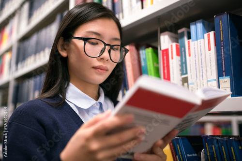 Junge Studentin liest ein Buch in der Bücherei