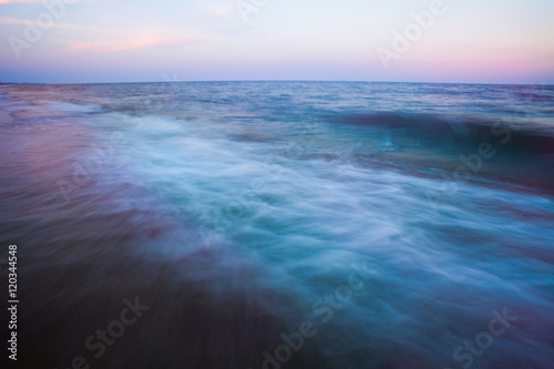 Waves motion during golden hour sunset over the sea.