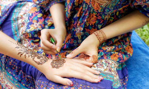 young woman mehendi artist painting henna on the hand photo