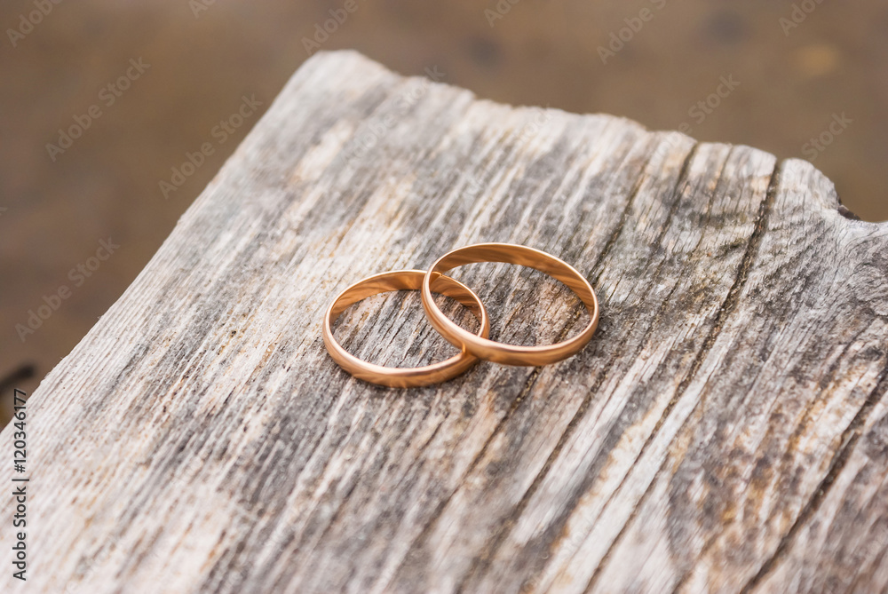 Two gold wedding rings lying on a wooden board of pier. Two gold wedding rings lying on a wooden board of pier.