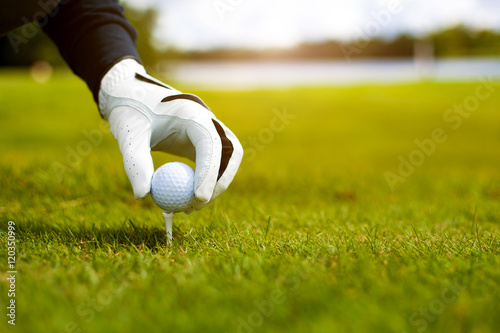 Hand hold golf ball with tee on course, close-up photo