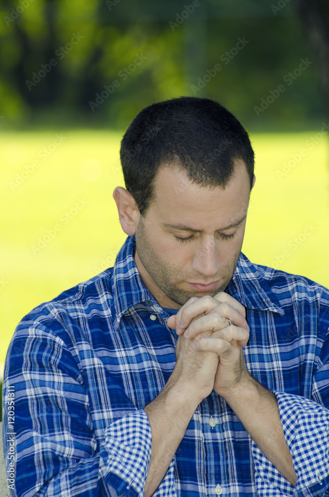 Man praying outdoors with a bright yellow and green sunlight background. Man praying outdoors with a bright yellow and green sunlight background.