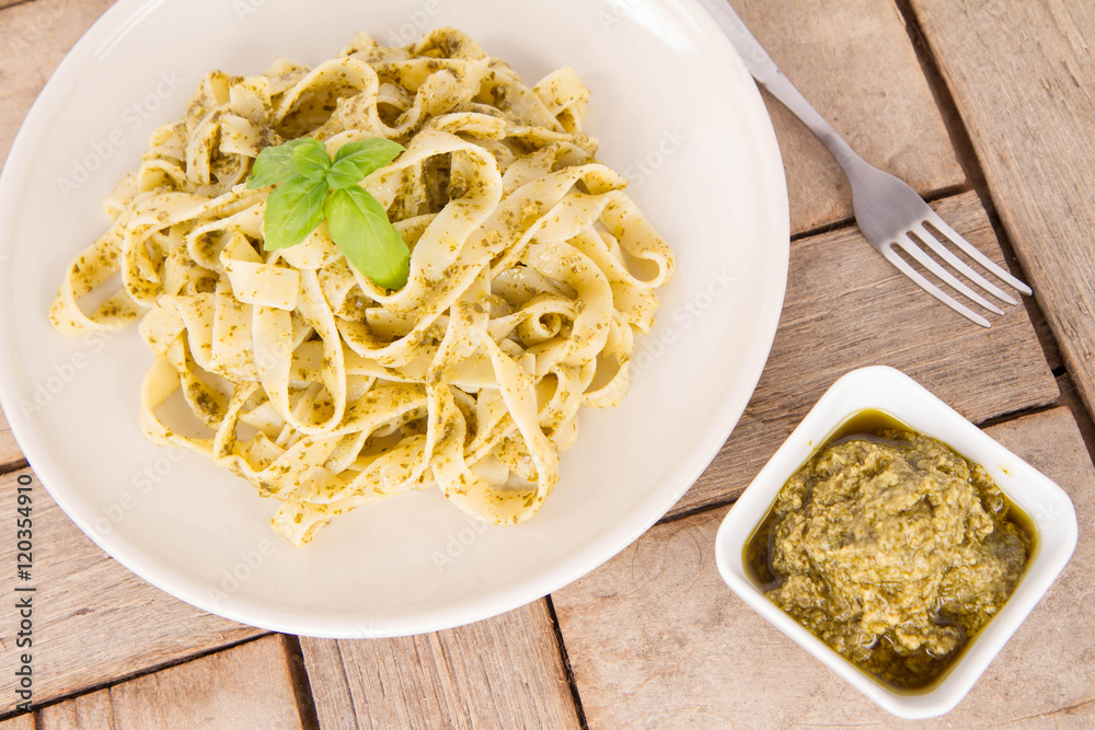 Tagliatelle with pesto decorated with basil on a wooden background