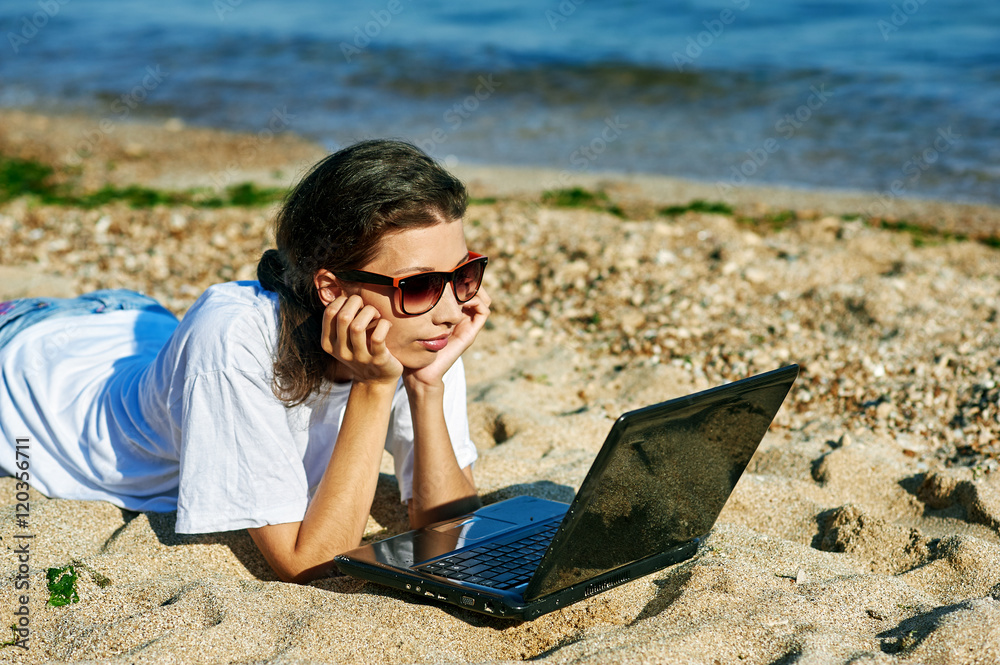 young girl with laptop at the sea