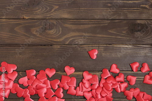 Lot bulk red hearts on a wooden table.
