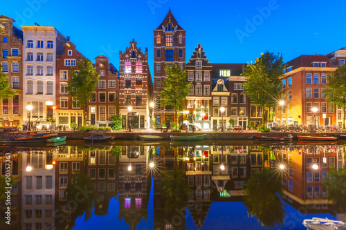 Night city view of Amsterdam canal Herengracht with typical dutch houses and their reflections, Holland, Netherlands.