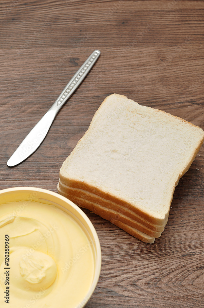 Butter, bread and a knife isolated on a wooden background