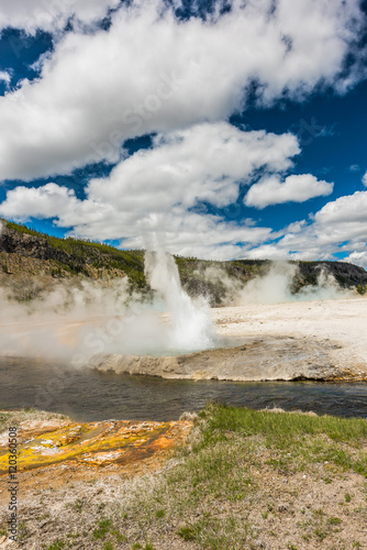 Geyser spurting water near Firehole river at Grand Prismatic spring near Midway Basin in Yellowstone National park