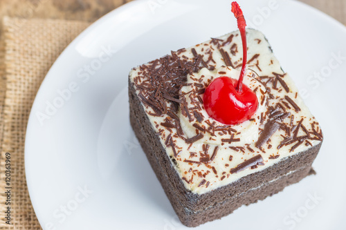 Chocolate cake with cherries on wooden background