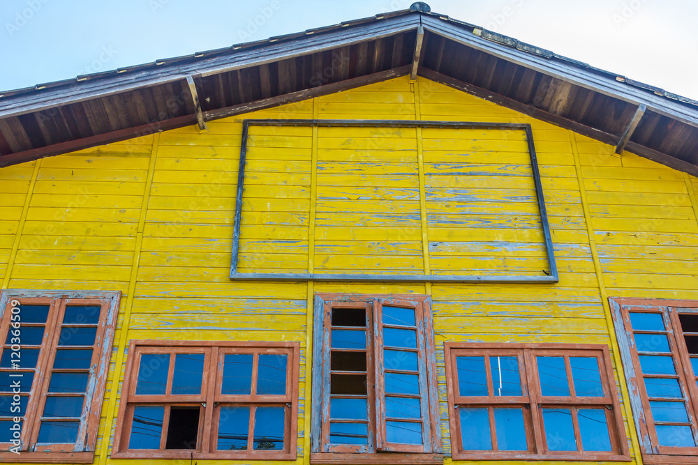 Casa amarela de madeira com muitas janelas.