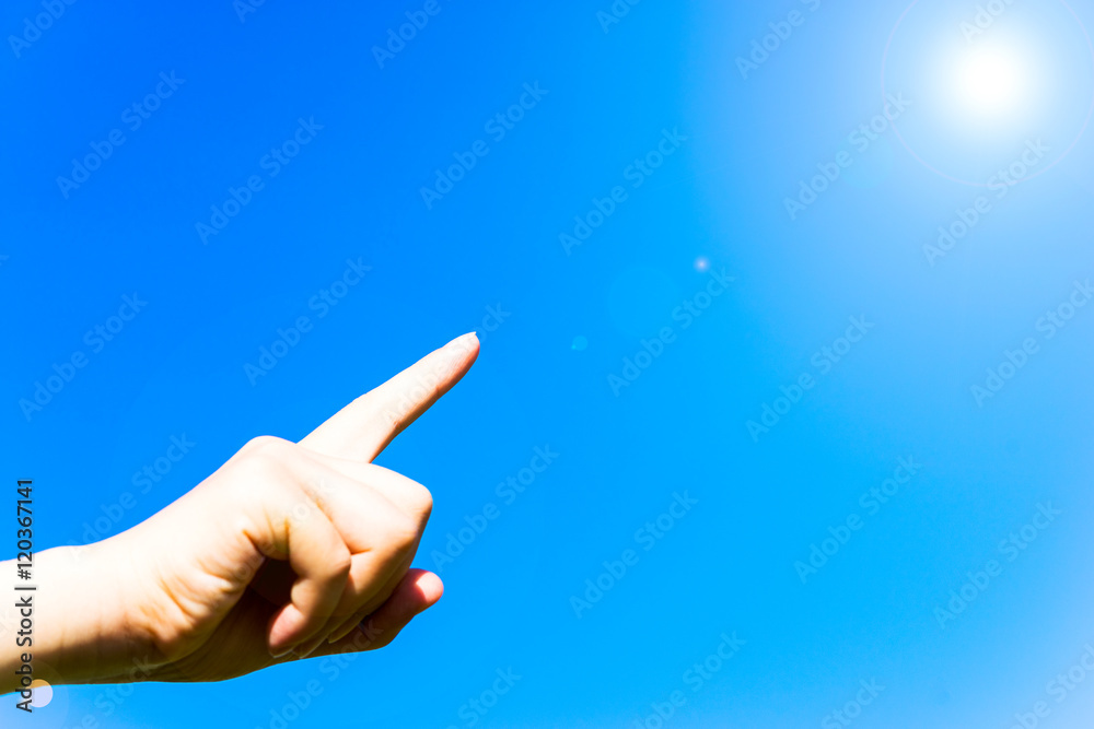 Female pointing finger under blue sky, with lens flare Female pointing finger under blue sky, with lens flare