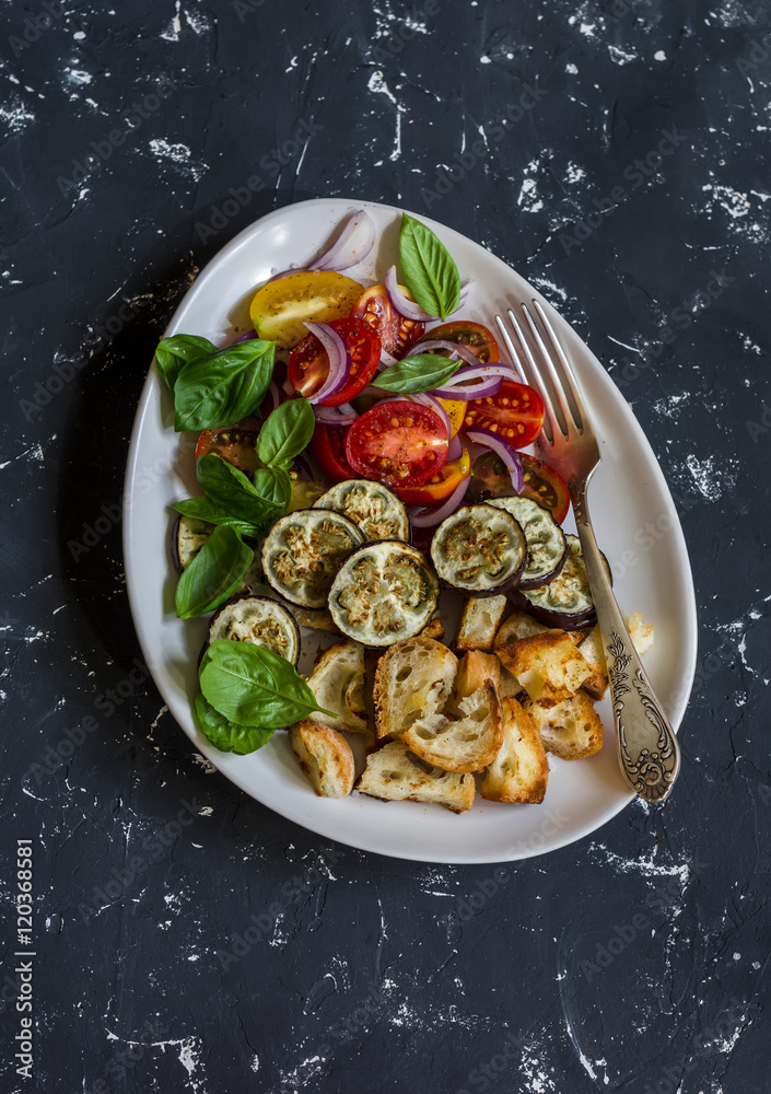 Roasted eggplant panzanella on a dark background, top view. Roasted eggplant panzanella on a dark background, top view.