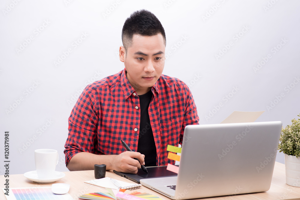 Happy designer working on his laptop in creative office Happy designer working on his laptop in creative office