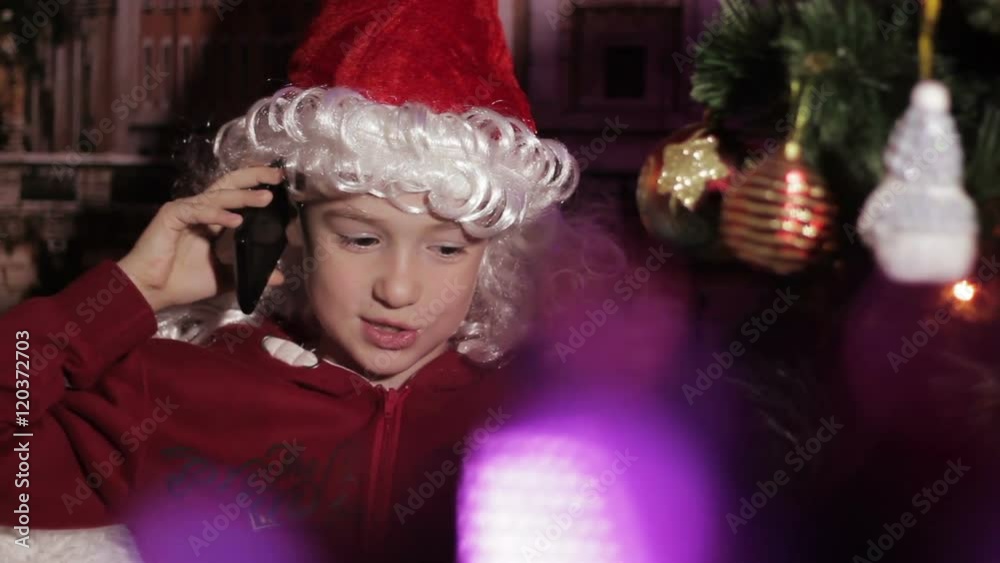 Santa Little boy talking on the phone at the Christmas tree Santa Little boy talking on the phone at the Christmas tree