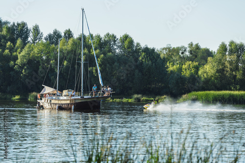 sailboat sailing on the river with deflated sails. Against the backdrop of the forest photo