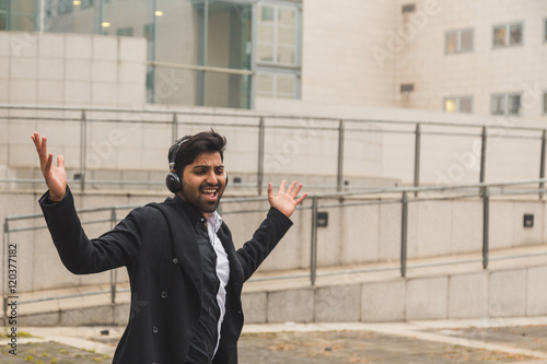 Handsome Indian man listening to music in an urban context