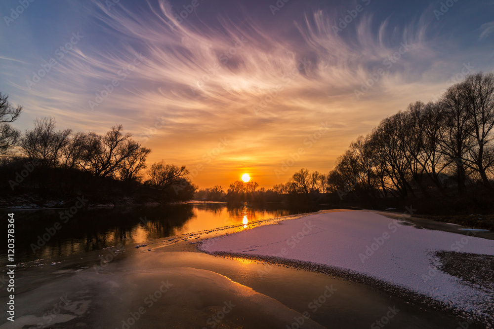 Beautiful sunset reflection in the river, in winter, on a cold freezing evening