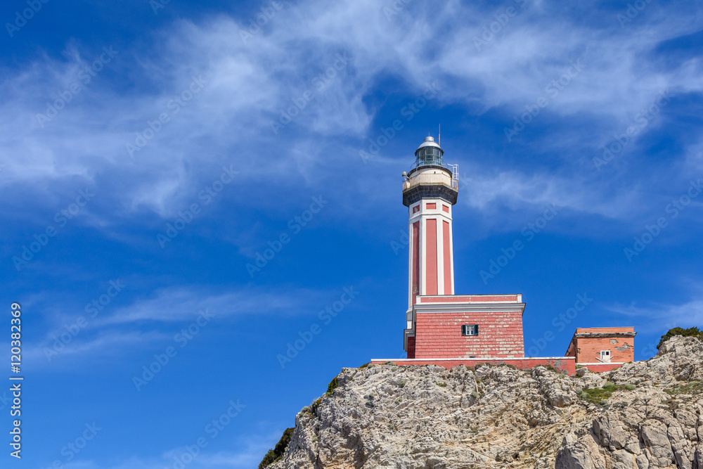 Lighthouse on a cliff in day time. Horizontal image with red and