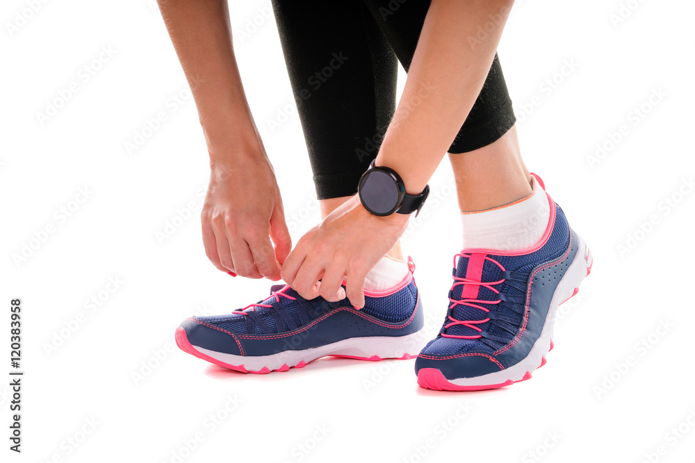 Lifestyle, sport and technology. Close up of female hands with smartwatch tying sneakers. Isolated on white. Lifestyle, sport and technology. Close up of female hands with smartwatch tying sneakers. Isolated on white.