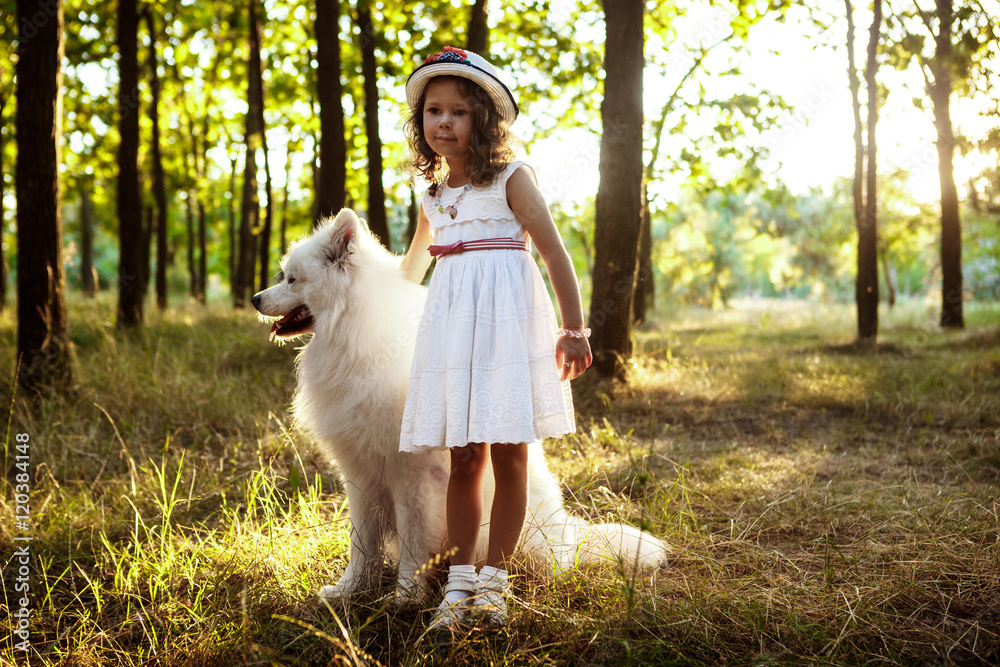 Young girl walking, playing with dog in park at sunset.