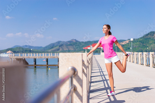 Sport lifestyle. Exercising outdoor. Young pretty woman stretching on the sea shore. © luengo_ua