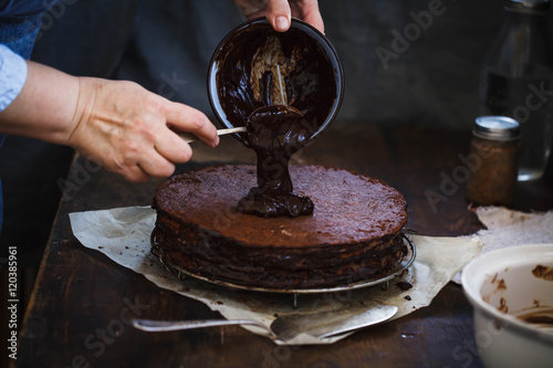 Chocolate ganache tart. Chef's hand spreading chocolate ganache glazed over torte