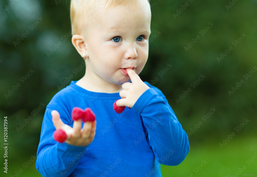 Young girl is holding raspberries on her fingers Young girl is holding raspberries on her fingers